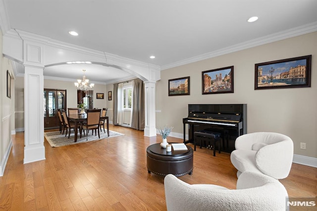 living area featuring ornate columns, arched walkways, baseboards, and an inviting chandelier