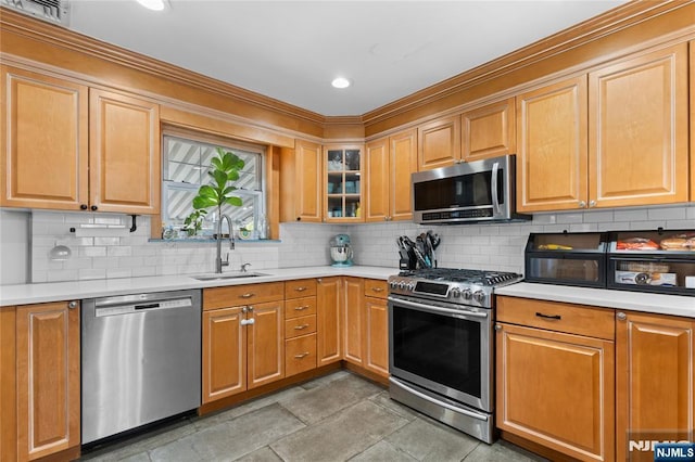 kitchen with stainless steel appliances, light countertops, a sink, and backsplash