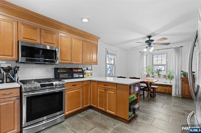 kitchen featuring stainless steel appliances, a peninsula, light countertops, and radiator