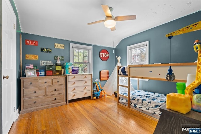 bedroom with hardwood / wood-style floors, lofted ceiling, ceiling fan, and multiple windows