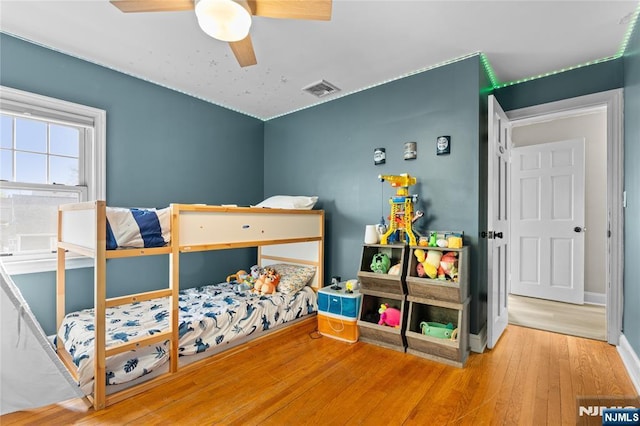 bedroom with visible vents, baseboards, a ceiling fan, and wood finished floors