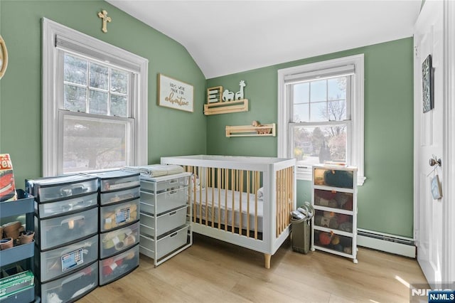 bedroom with a baseboard heating unit, wood finished floors, and multiple windows