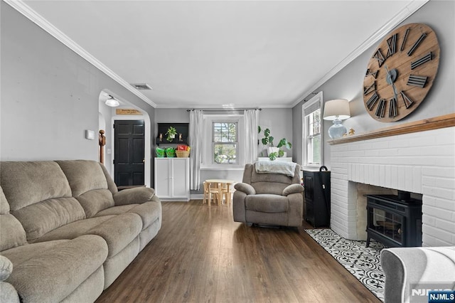 living room featuring crown molding, wood finished floors, visible vents, and a fireplace