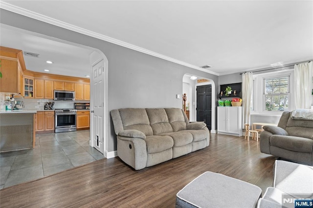 living room with recessed lighting, light wood finished floors, visible vents, arched walkways, and crown molding