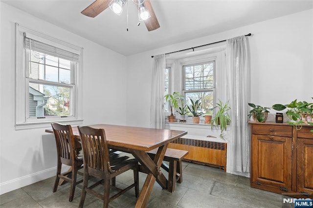 dining area featuring radiator, plenty of natural light, a ceiling fan, and baseboards