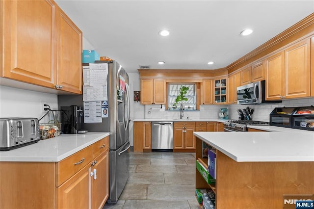 kitchen with light countertops, tasteful backsplash, stone finish flooring, and appliances with stainless steel finishes