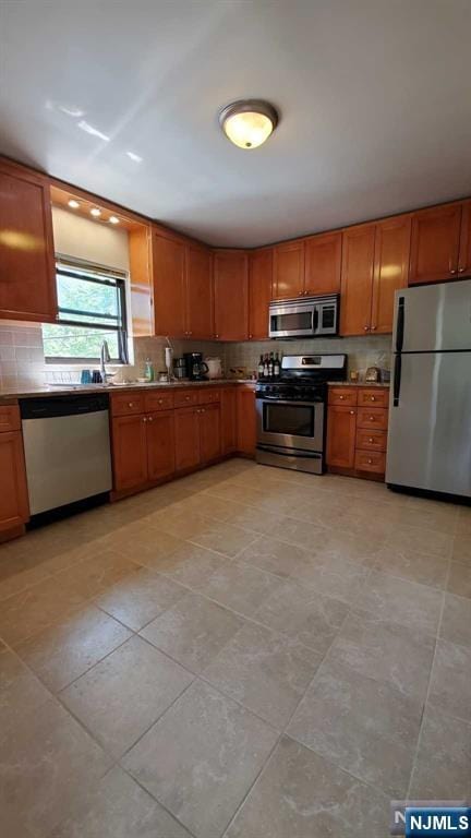 kitchen featuring decorative backsplash, stainless steel appliances, brown cabinets, and light tile patterned flooring