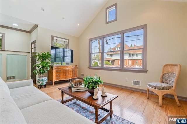 living area with light wood-style floors, baseboards, visible vents, and high vaulted ceiling