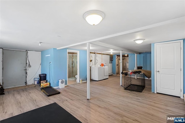 finished basement featuring washer and dryer, light wood finished floors, and baseboards
