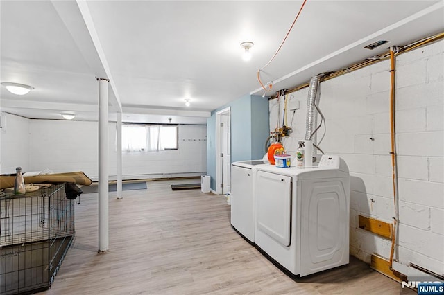 washroom featuring concrete block wall, light wood finished floors, independent washer and dryer, and laundry area
