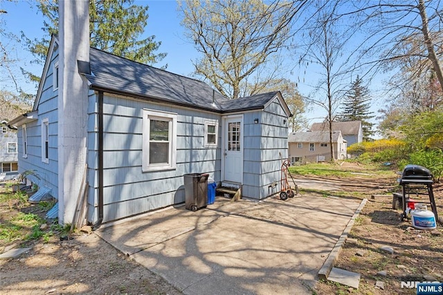 back of house with a shingled roof and a patio area