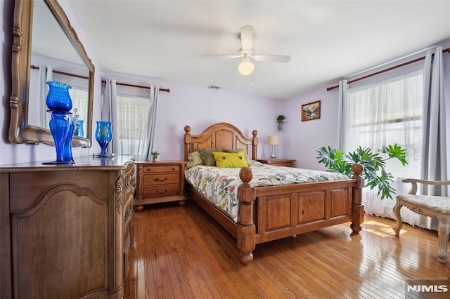 bedroom featuring wood-type flooring, multiple windows, and ceiling fan