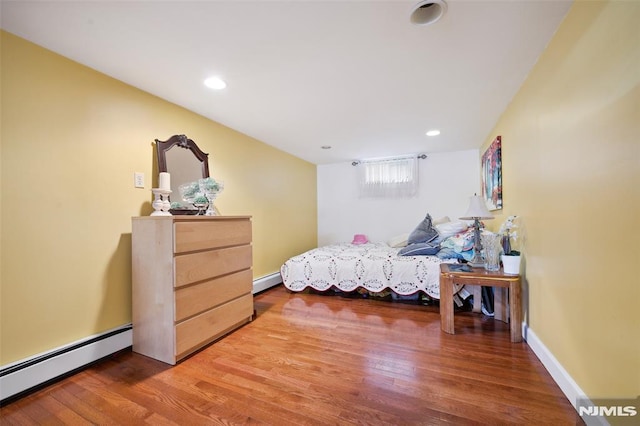bedroom with baseboards, wood finished floors, recessed lighting, and a baseboard radiator