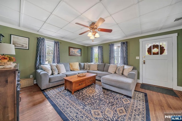 living area with a ceiling fan, ornamental molding, and wood-type flooring