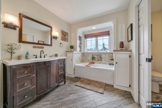 bathroom with toilet, a garden tub, and vanity