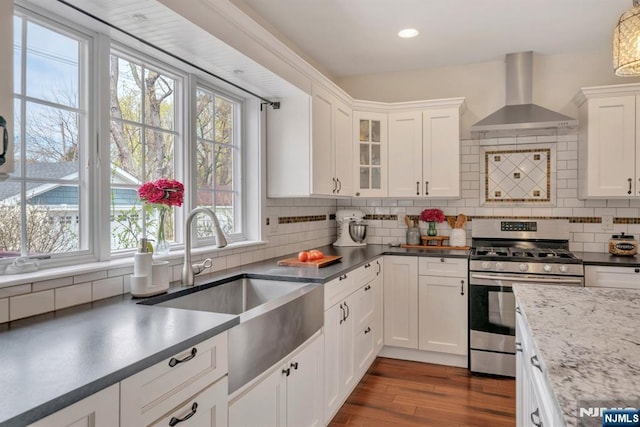 kitchen featuring a sink, a wealth of natural light, gas range, and wall chimney range hood