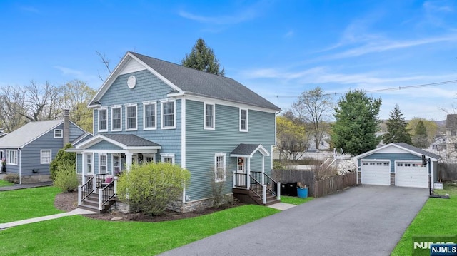 view of front of house with a front lawn, a shingled roof, an outbuilding, a detached garage, and fence
