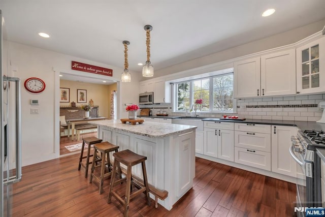 kitchen featuring appliances with stainless steel finishes, white cabinetry, dark wood finished floors, and backsplash