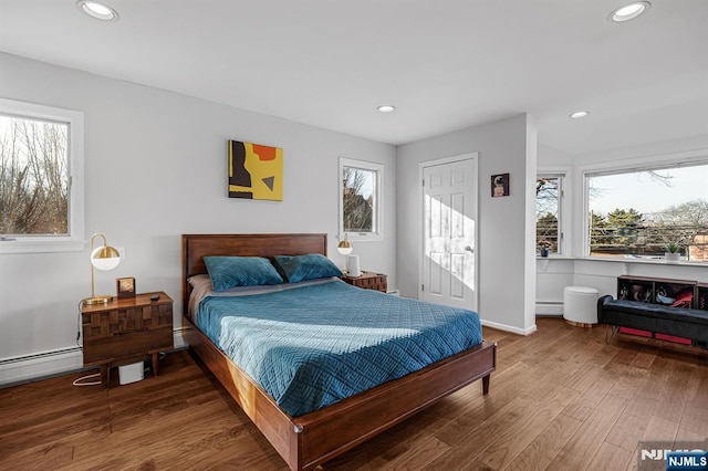 bedroom with baseboard heating, baseboards, wood finished floors, and recessed lighting