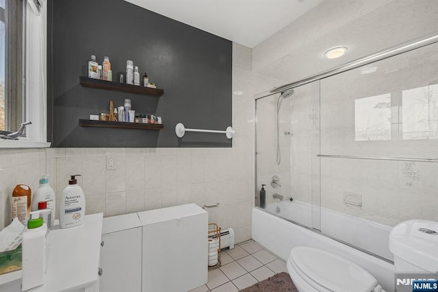 bathroom with tile patterned flooring, enclosed tub / shower combo, toilet, tile walls, and a baseboard radiator