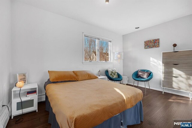 bedroom featuring wood-type flooring, a baseboard radiator, and baseboards