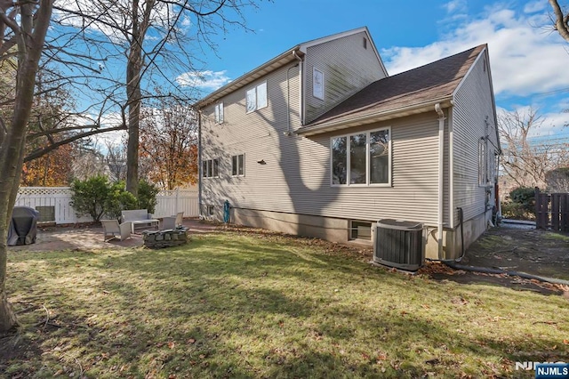 back of property featuring fence, a fire pit, a yard, and central AC unit