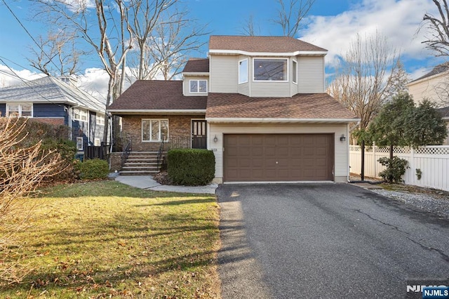 traditional-style house featuring fence, a garage, a shingled roof, a front yard, and aphalt driveway