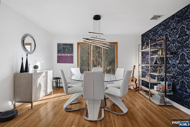 dining area featuring wallpapered walls, wood finished floors, visible vents, and baseboards