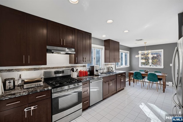 kitchen featuring dark brown cabinets, recessed lighting, backsplash, under cabinet range hood, and appliances with stainless steel finishes