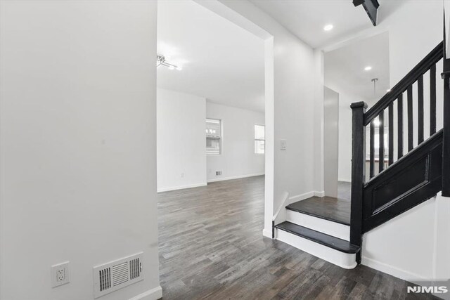 staircase with wood finished floors, visible vents, and baseboards