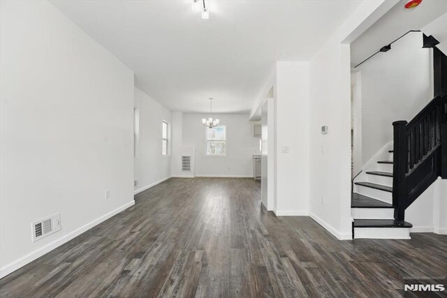 unfurnished living room with a chandelier, stairway, baseboards, and dark wood-type flooring