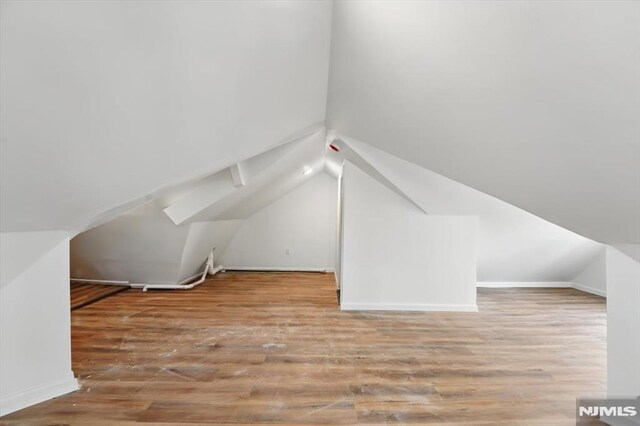 bonus room featuring baseboards, vaulted ceiling, and wood finished floors