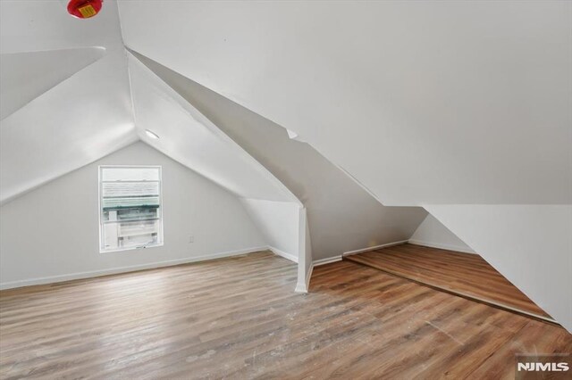 additional living space with lofted ceiling, wood finished floors, and baseboards