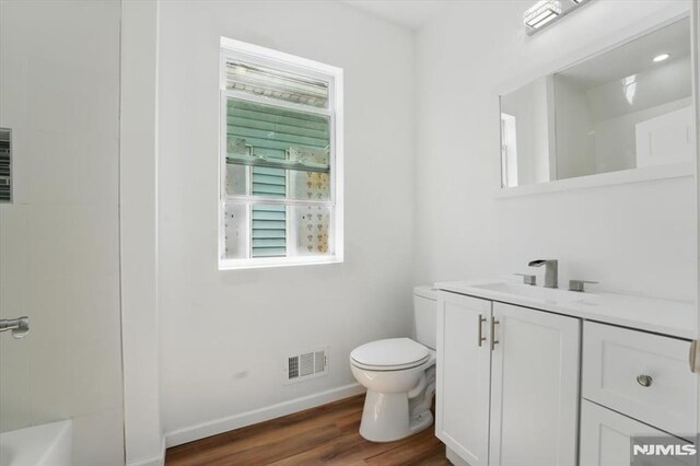 bathroom with toilet, baseboards, visible vents, wood finished floors, and vanity