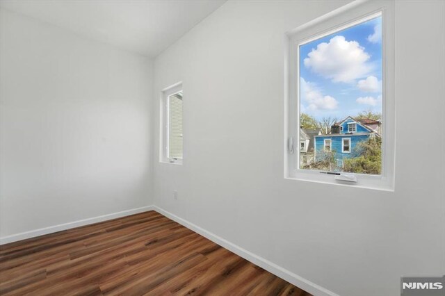 spare room featuring baseboards and dark wood finished floors