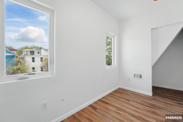 spare room with baseboards, wood finished floors, and visible vents