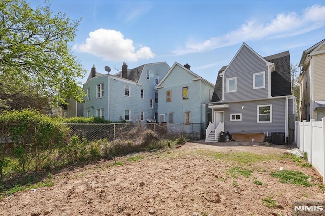rear view of property featuring a fenced backyard and central AC