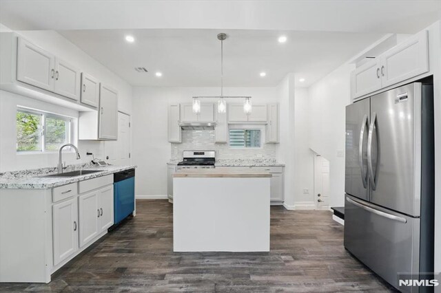 kitchen with dark wood-style floors, a sink, white cabinetry, backsplash, and appliances with stainless steel finishes