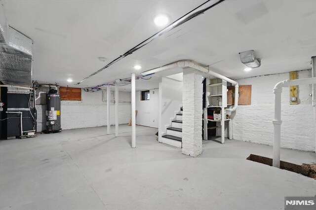 unfinished below grade area featuring water heater, heating unit, and stairs