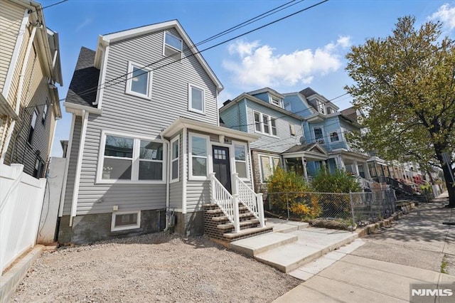 view of front facade with fence, entry steps, and a residential view