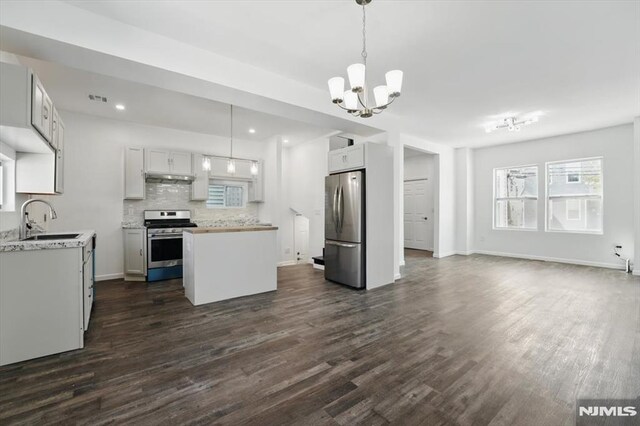 kitchen with dark wood-style flooring, a center island, a sink, appliances with stainless steel finishes, and a notable chandelier