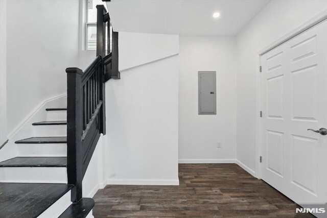 stairs featuring baseboards, wood finished floors, electric panel, and recessed lighting