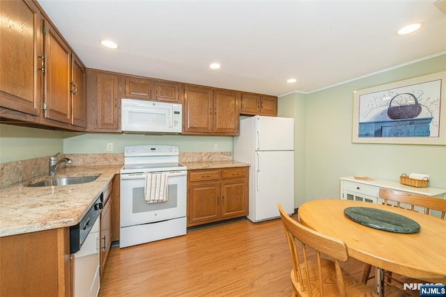 kitchen featuring brown cabinets, ornamental molding, a sink, white appliances, and light wood-type flooring