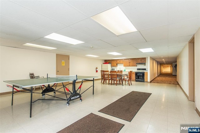 recreation room featuring baseboards and a drop ceiling