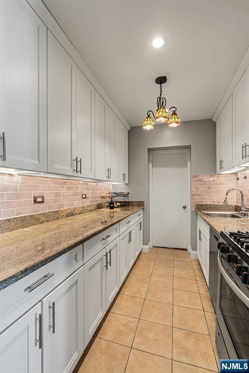 kitchen with a sink, stainless steel gas stove, decorative backsplash, white cabinets, and dishwashing machine
