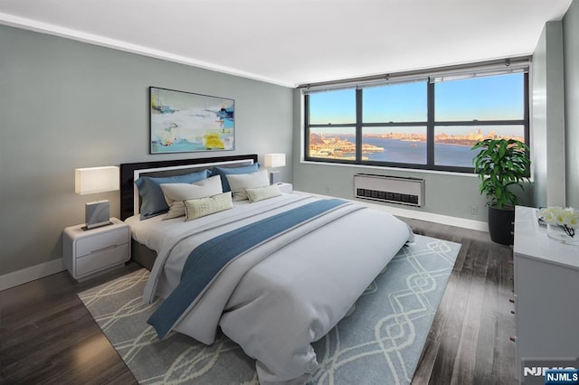 bedroom featuring baseboards, dark wood finished floors, heating unit, and a wall unit AC