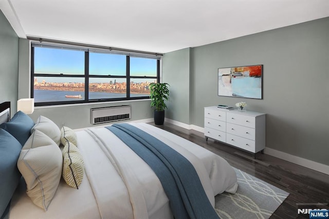 bedroom with baseboards, wood finished floors, heating unit, and an AC wall unit