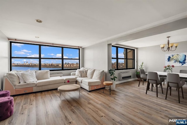 living room with a chandelier, wood finished floors, a wall mounted AC, and plenty of natural light