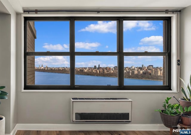 detailed view of a water view, wood finished floors, baseboards, and heating unit