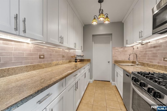 kitchen with a sink, appliances with stainless steel finishes, light stone counters, and white cabinetry